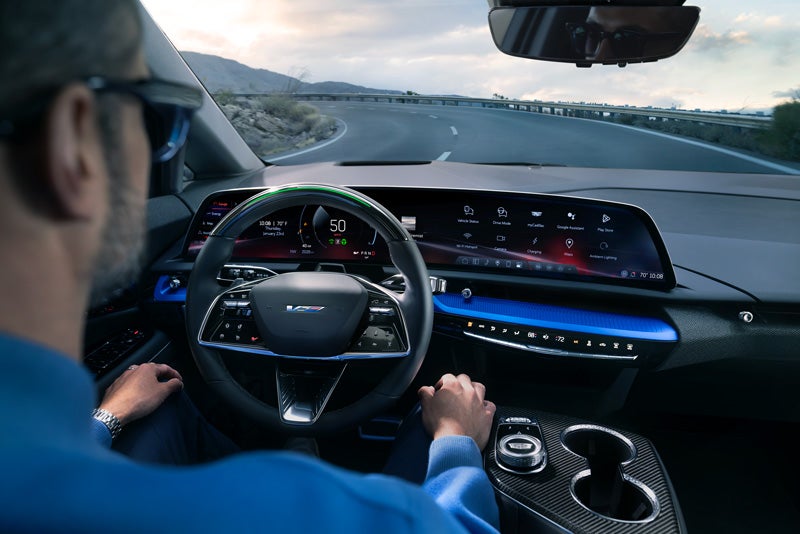 Front View of the 2026 OPTIQ-V Driving Through the Dusk Utilizing its Headlights | Cadillac of Santa Fe in Santa Fe NM