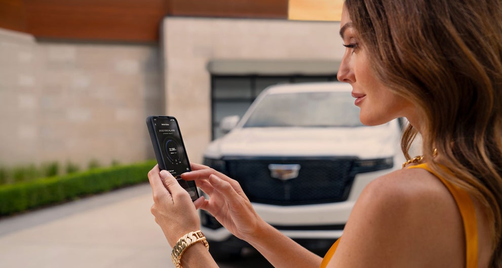 lady checking her mobile with a Cadillac vehicle background | Cadillac of Santa Fe in Santa Fe NM